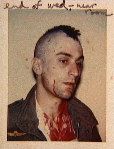 Polaroid de continuidad: un hombre con cresta y sangre en la cara y el cuello.